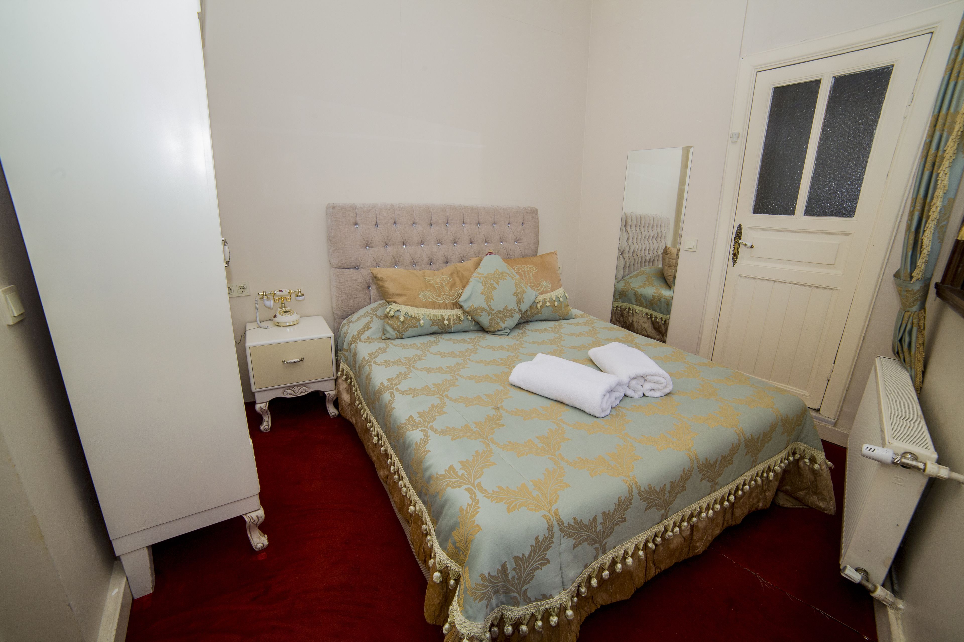 A bedroom with a bed, nightstand, dresser, and a door.