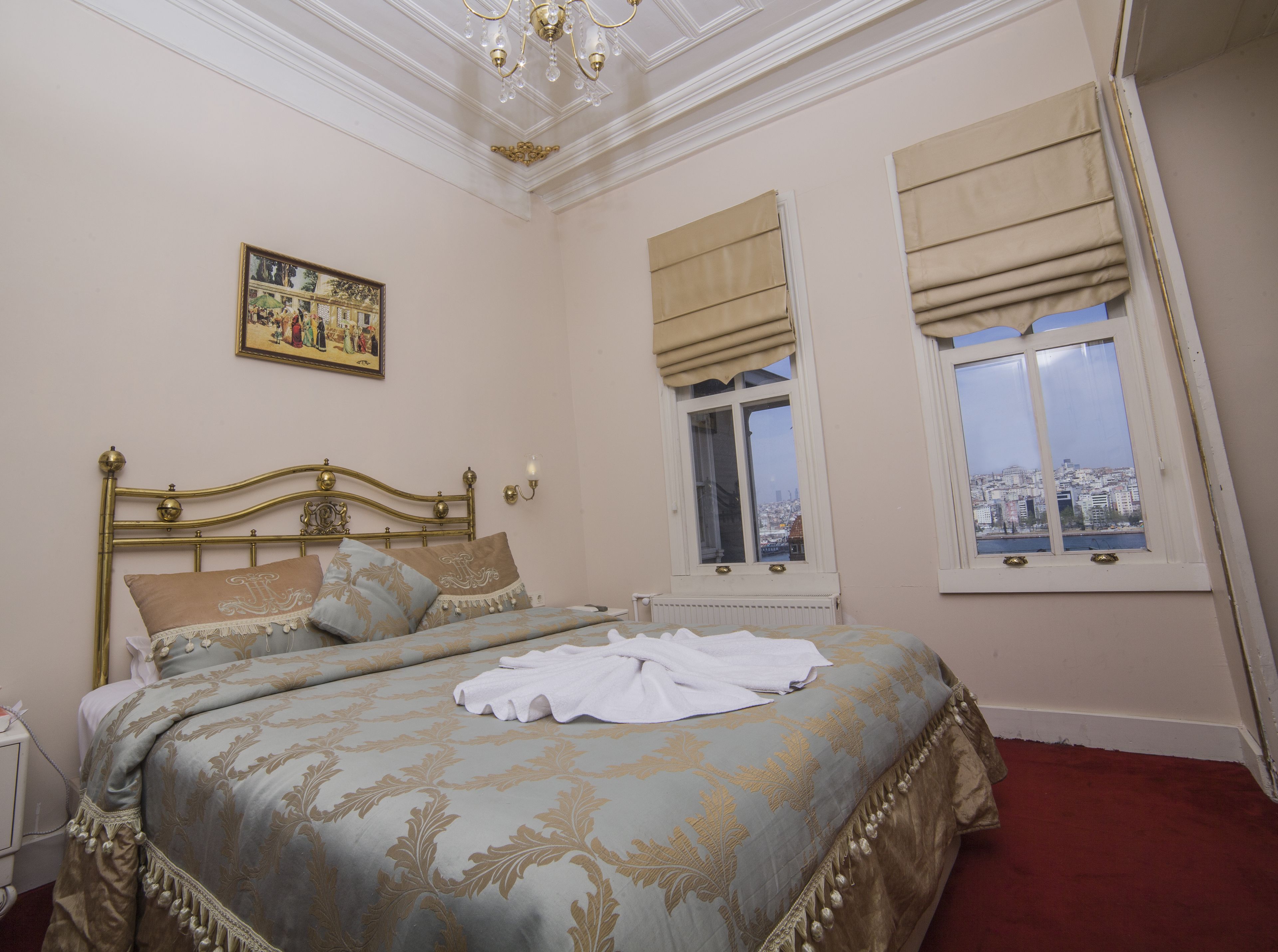 Een slaapkamer met een bed, een schilderij aan de muur, een raam met uitzicht en een kroonluchter.
