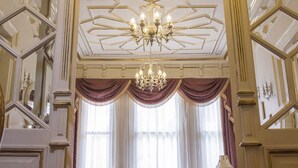 A grand room with a chandelier, a sofa, and a large window with curtains. - HHK Hotel (Istanbul)