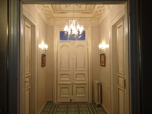 A hallway with double doors, a chandelier, wall sconces, and patterned floor tiles. - HHK Hotel (Istanbul)