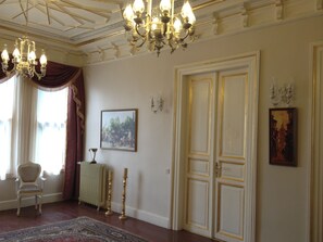 A room with a chandelier, a framed painting, a door, and a radiator. - HHK Hotel (Istanbul)