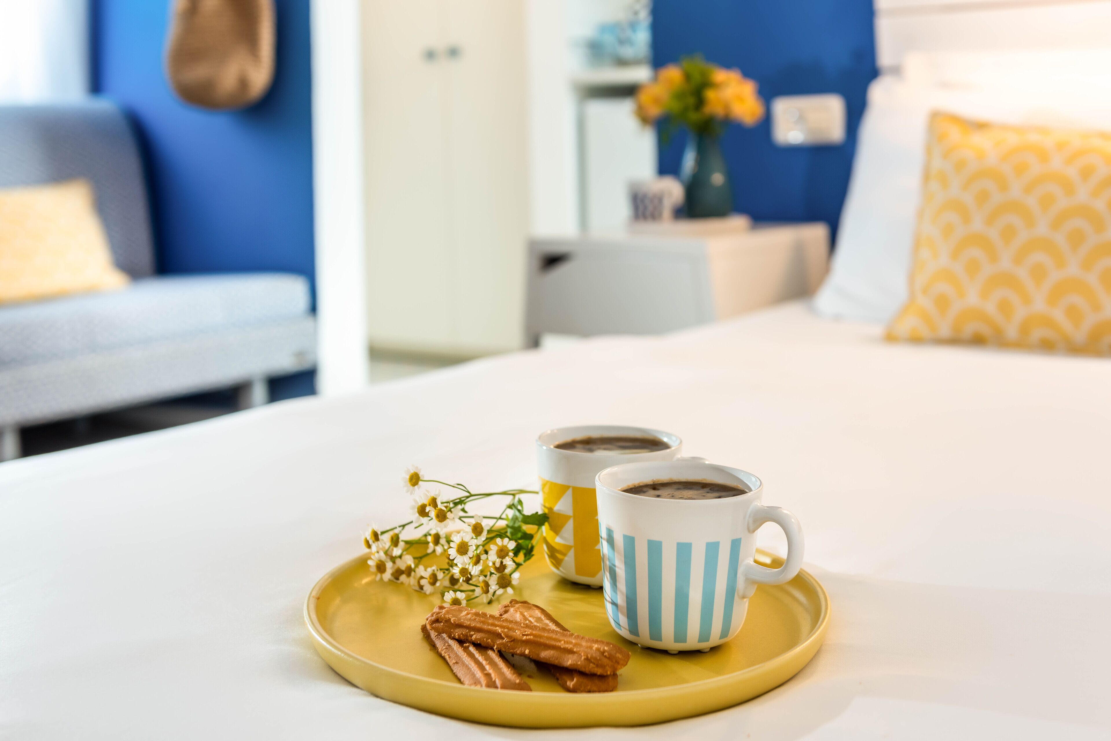 Un vassoio per la colazione con pasticcini e tazzine di caffè su un letto in una camera d'albergo.