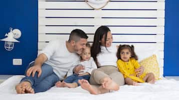 A family sitting on a bed with a white headboard and a blue wall.