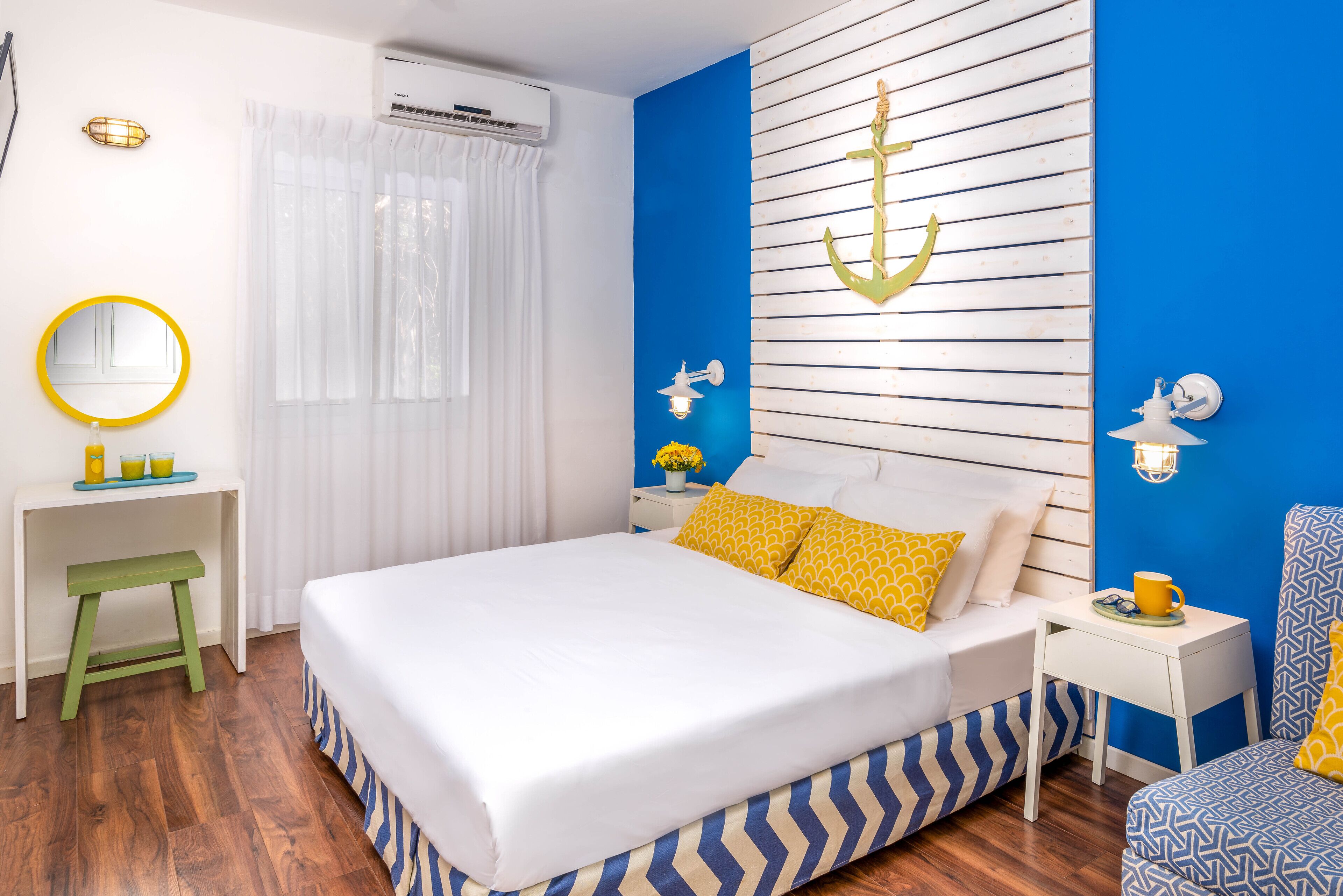 A bedroom with a bed, bedside tables, a mirror, and a wall-mounted air conditioner.