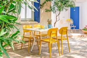 A patio with yellow chairs and a table, a potted plant, and a door with the number 30.