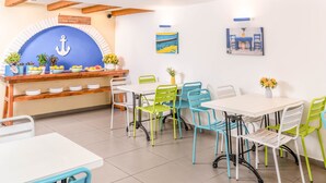 A dining area with a white table, colorful chairs, and a blue archway with an anchor decoration.