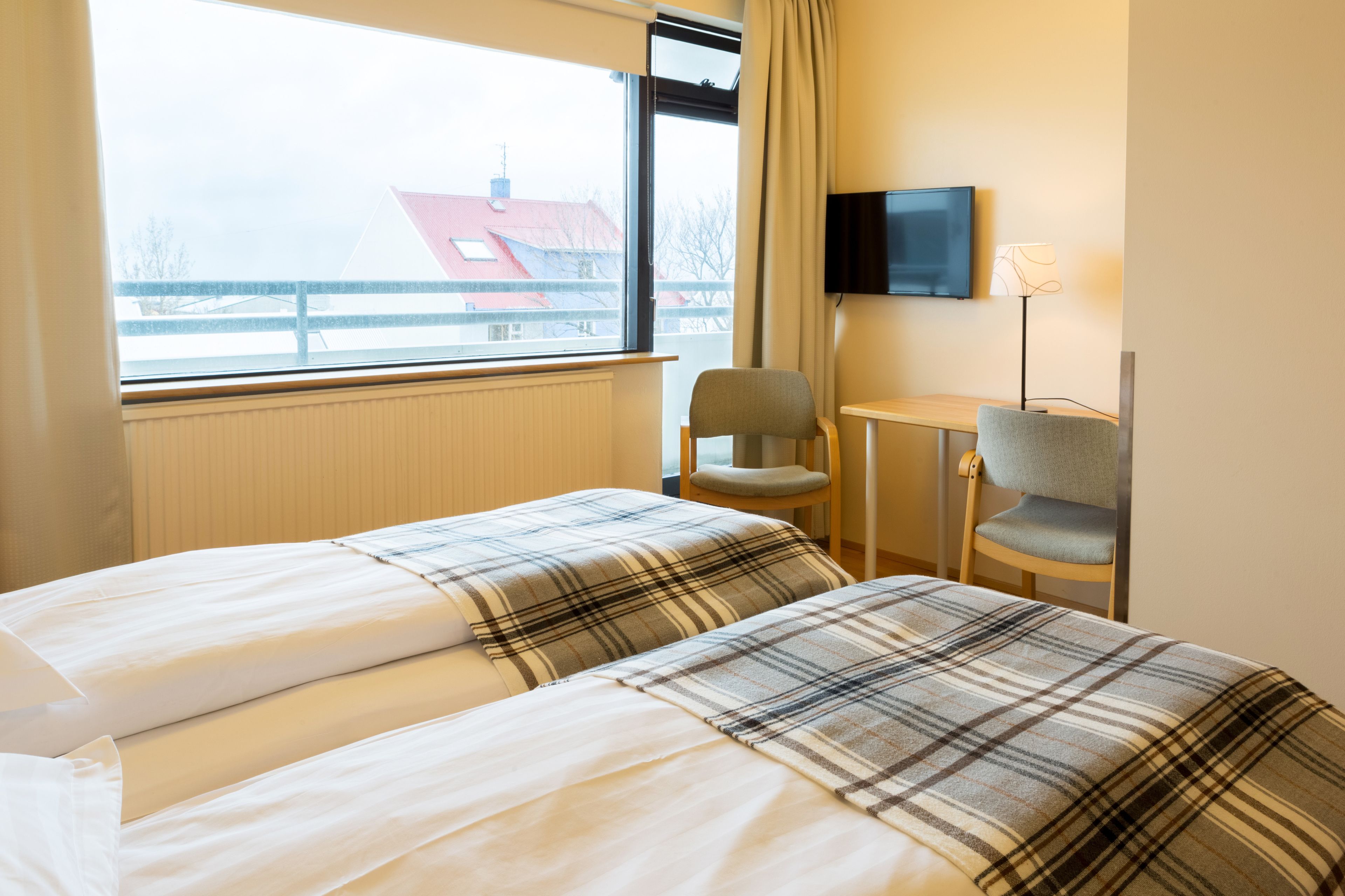 A hotel room with two beds, a TV, a desk, and a chair.