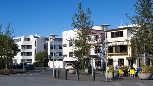 A café named 'café Loki' with outdoor seating, surrounded by modern buildings and trees. - Guesthouse Sunna (Reykjavik)