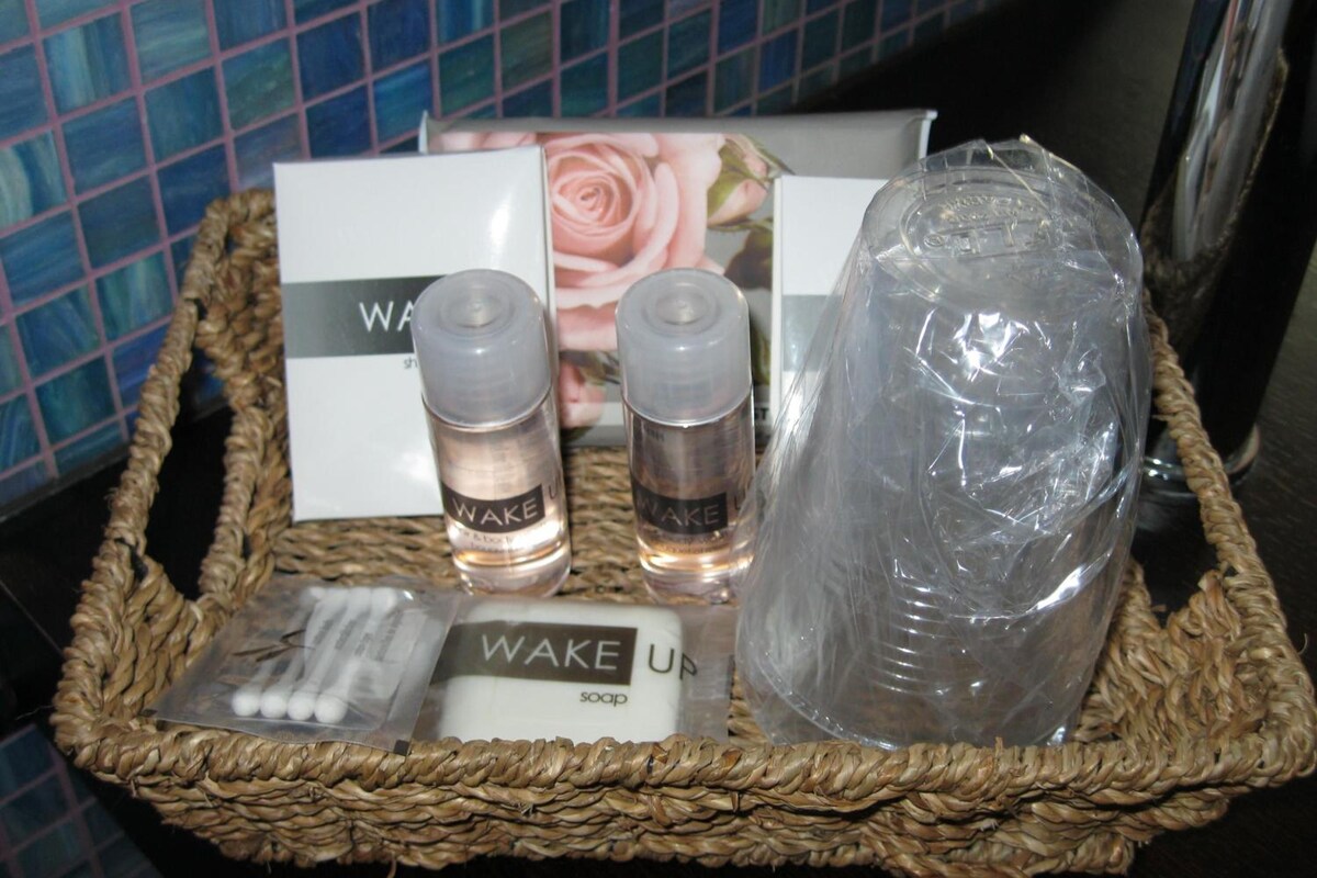 A wicker basket containing Wake Up soap, two bottles of Wake Up body wash, and a plastic container wrapped in plastic.