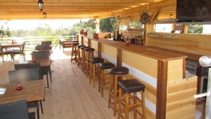 A wooden bar area with high stools, a television, and a view of the outdoors. - Ministar Hotel (Bodrum)