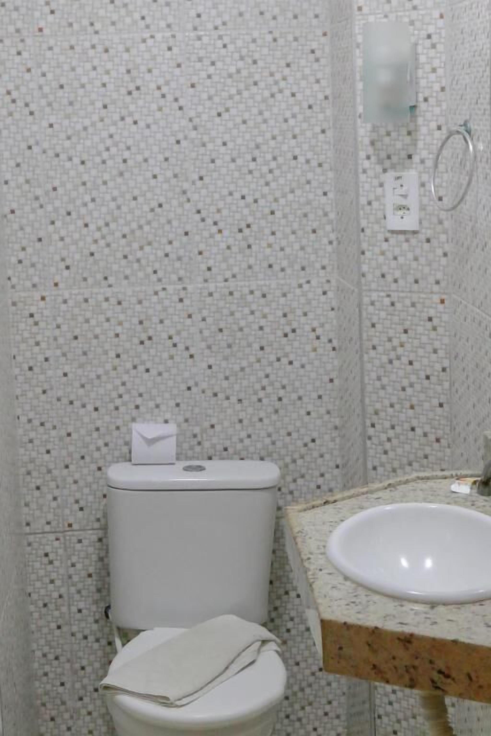 Une salle de bain avec des toilettes, un lavabo et des murs carrelés.