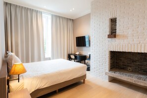 A bedroom with a bed, a desk, a television, and a fireplace. - Hotel Lodewijk Van Male (Bruges)