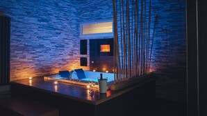 A modern bathroom with a stone wall, a bathtub, and a mirror. - Sweet Sleep (Naples)