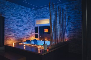 Een moderne badkamer met een stenen muur, een badkuip en een spiegel.