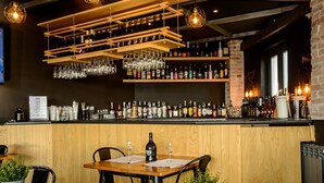 A bar area with wooden shelves stocked with bottles and glasses, a wooden counter, and tables with chairs. - Sweet Sleep (Naples)