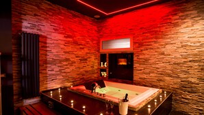 A modern spa room with a large bathtub, candles, and a bottle of champagne. - Sweet Sleep (Naples)
