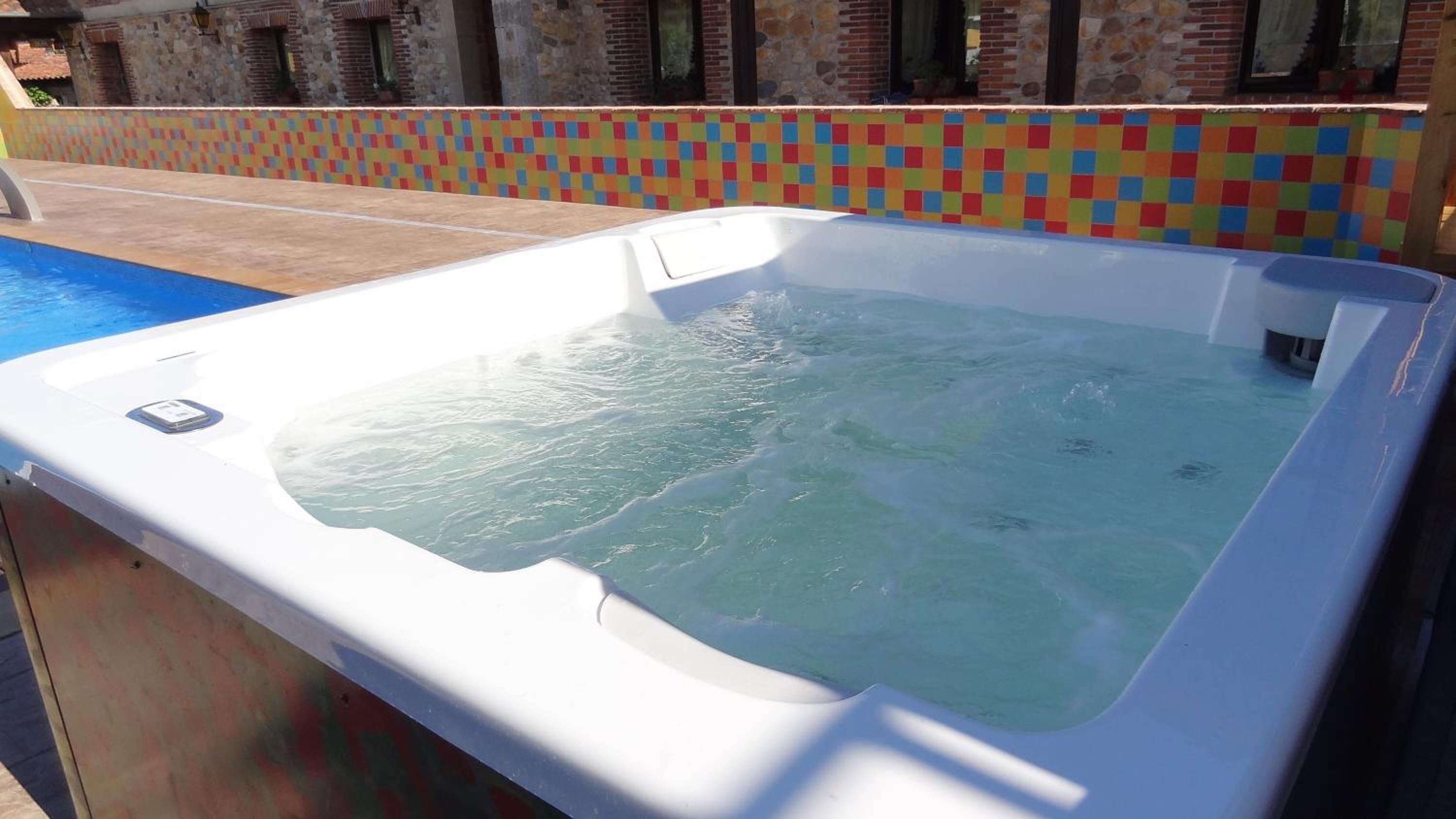 A hot tub with a tiled wall in the background.