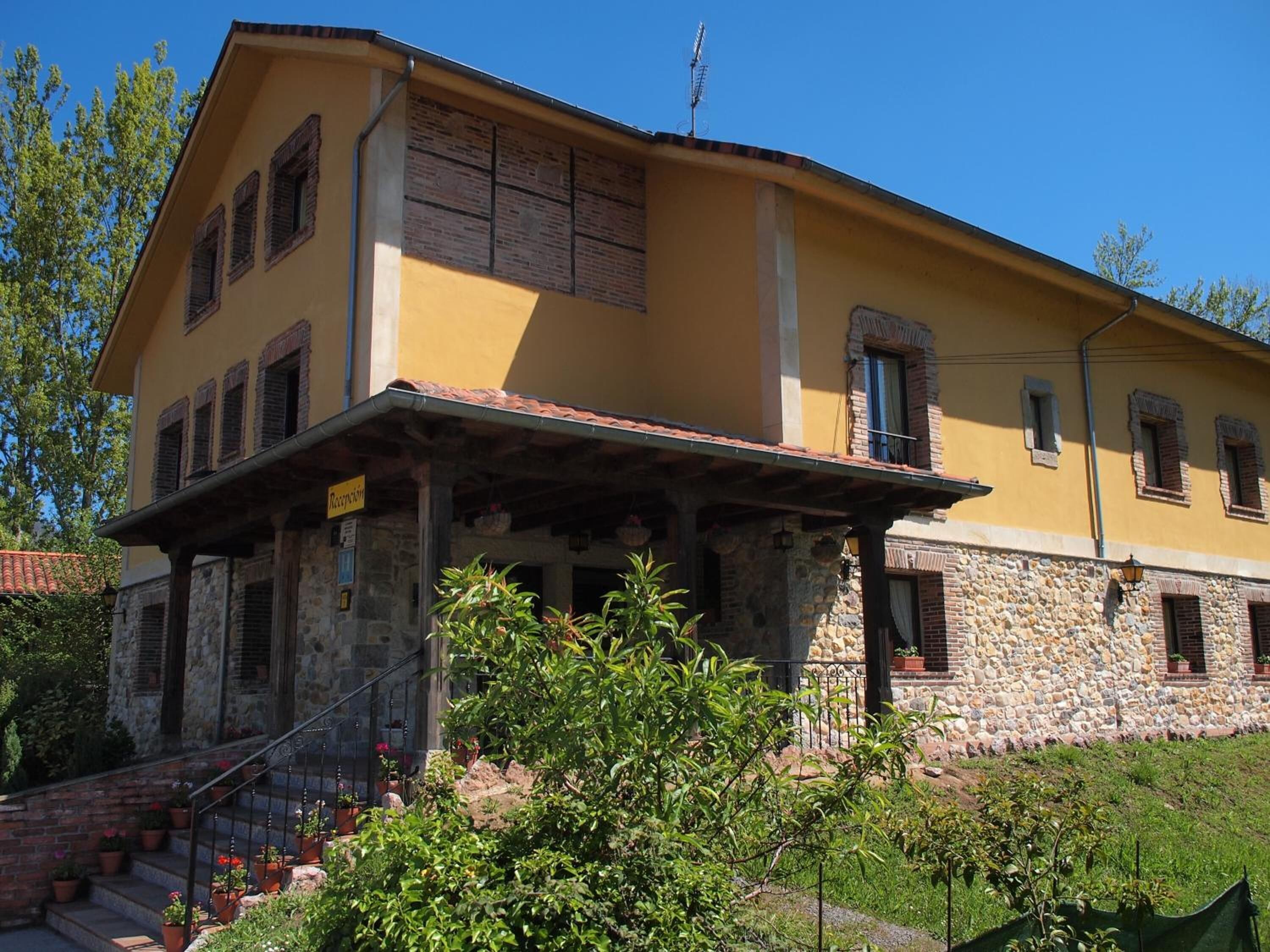 A two-story building with a yellow facade, stone base, and a sign indicating a reception area.