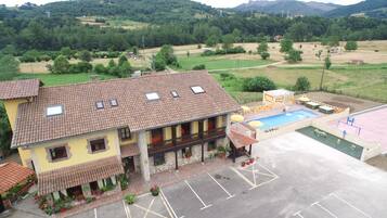 A two-story building with a tiled roof, a swimming pool, and a parking area.
