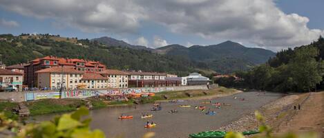 A riverside town with buildings along the riverbank and a mountainous backdrop.