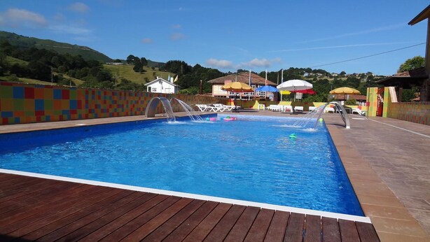 Una piscina con cubierta de madera, rodeada de paredes coloridas y sombrillas.