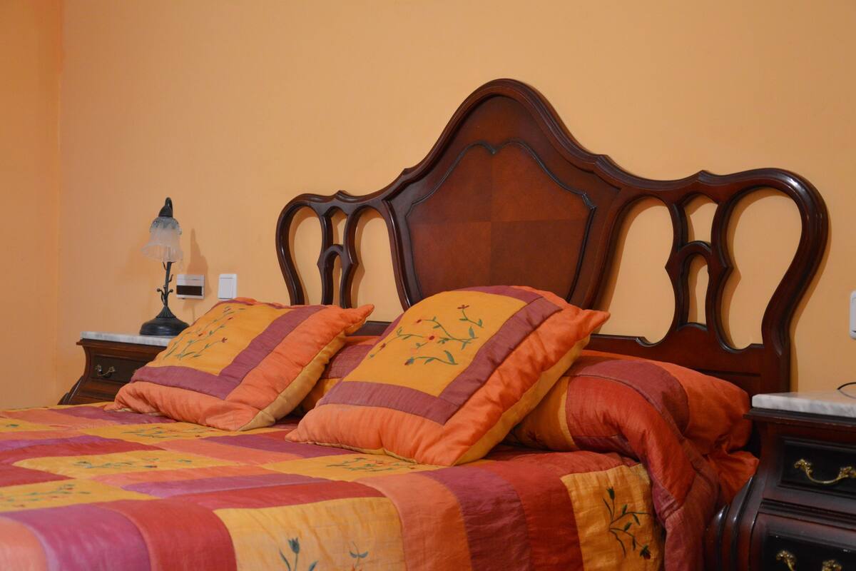 A bed with a wooden headboard, multiple pillows, and a quilt.
