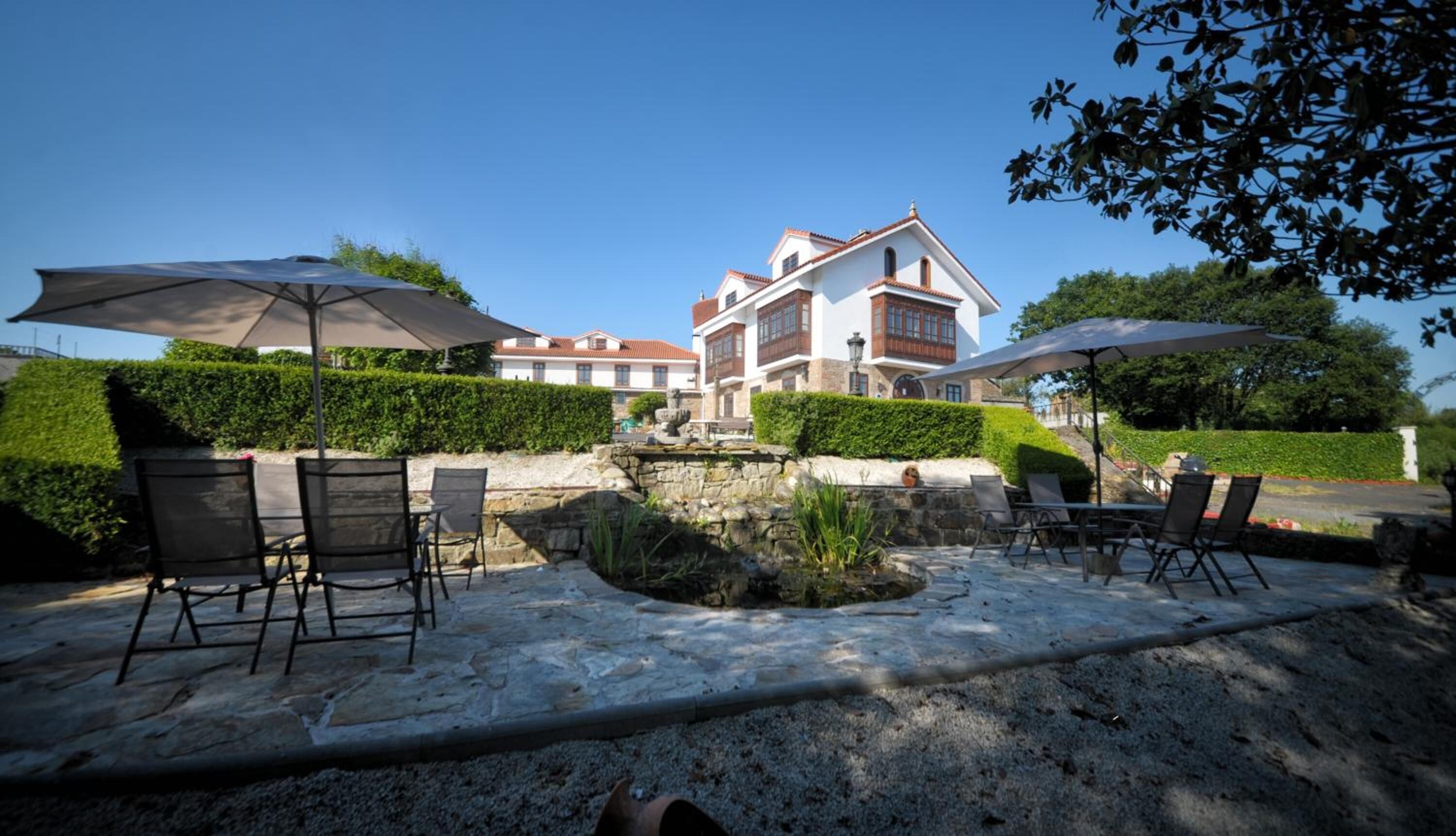 An outdoor patio area with stone flooring, outdoor seating, and umbrellas.