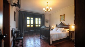 Un dormitorio tradicional con cama con dosel, un candelabro y vistas al exterior a través de amplias ventanas.