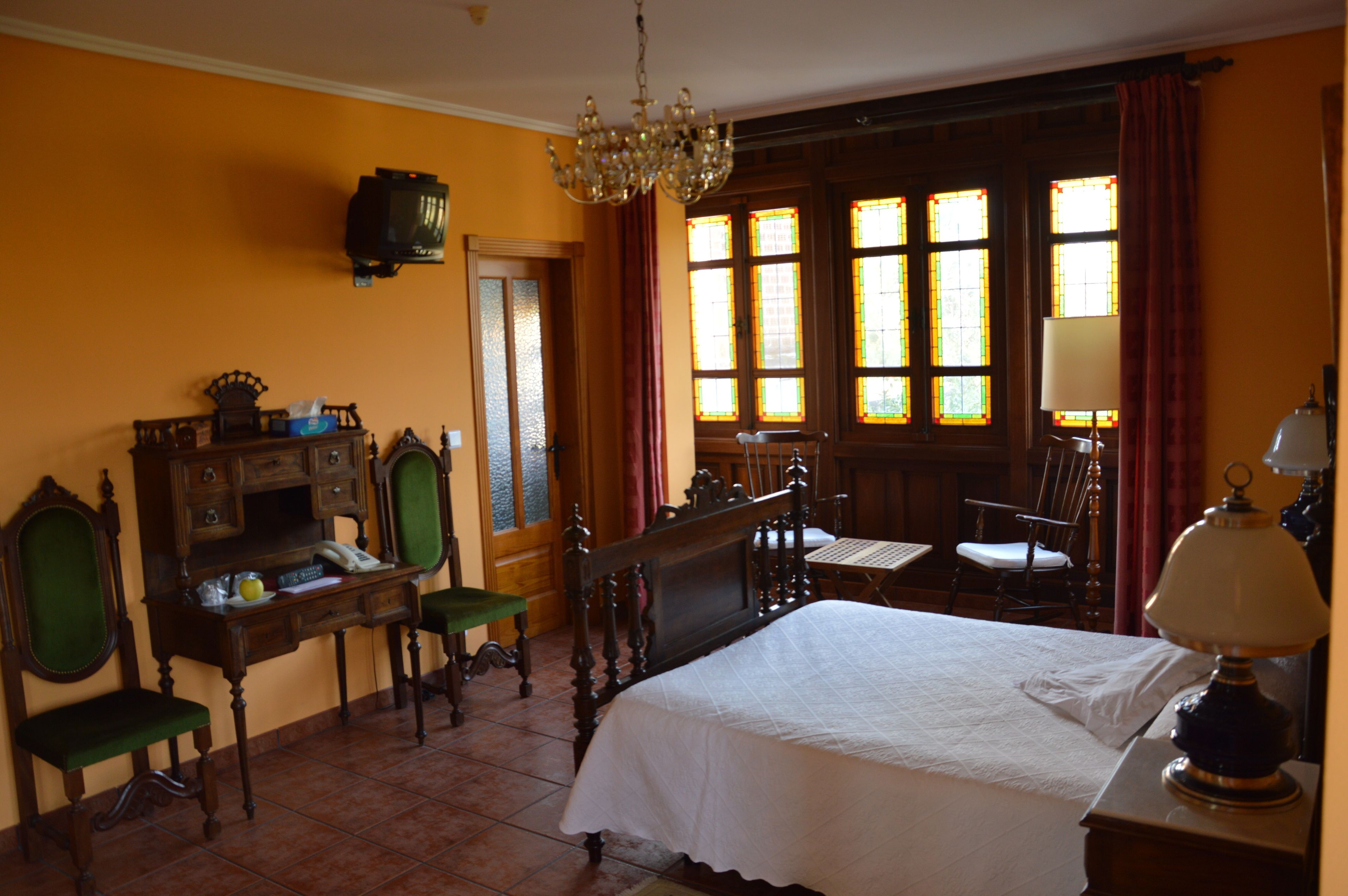 A room with a bed, a desk, a chair, and a table.