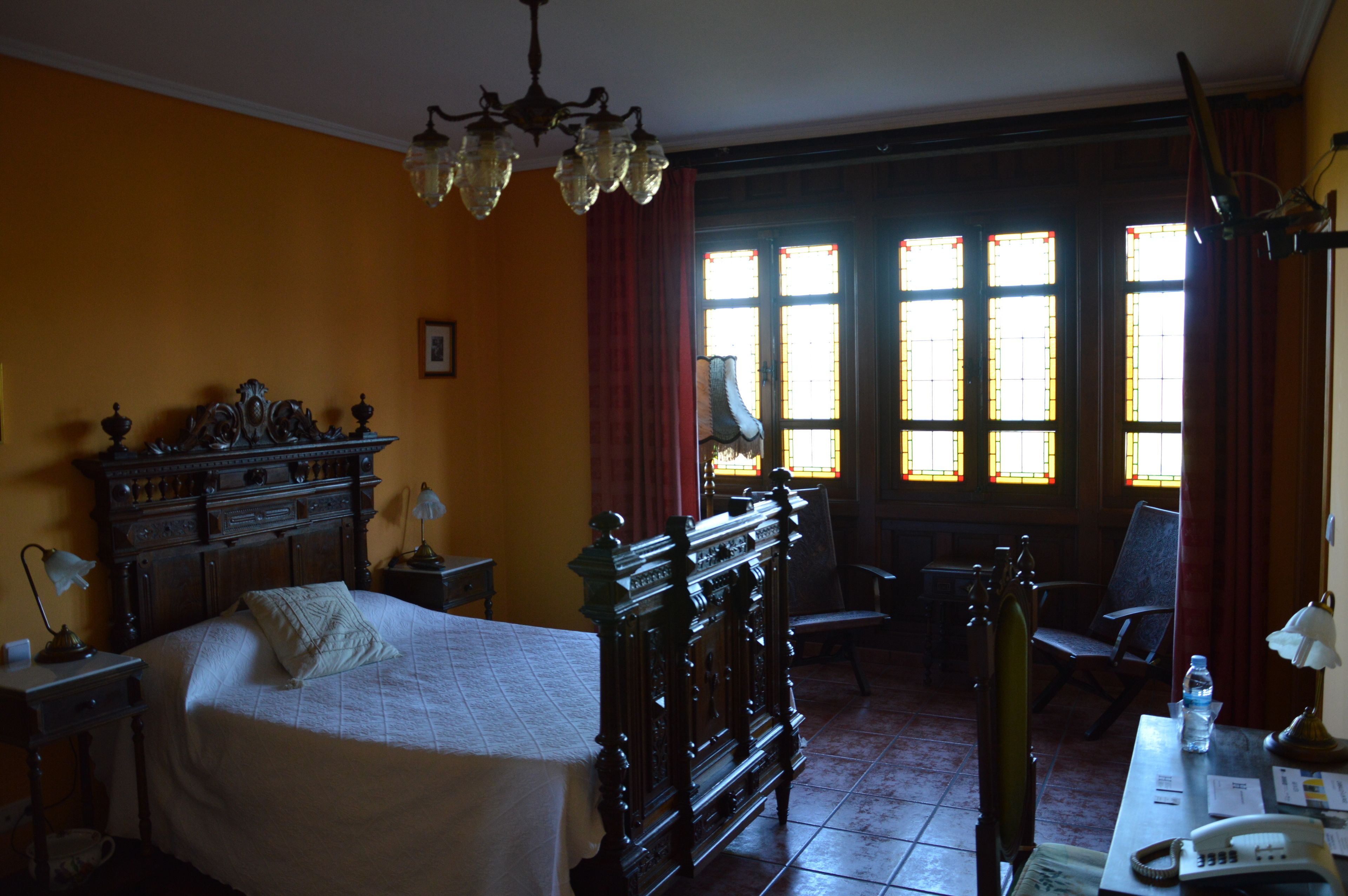 A room with a bed, a wooden dresser, a desk with a telephone, and a chair.