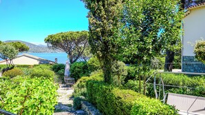 Un jardín con un banco, un sendero y vista al mar.