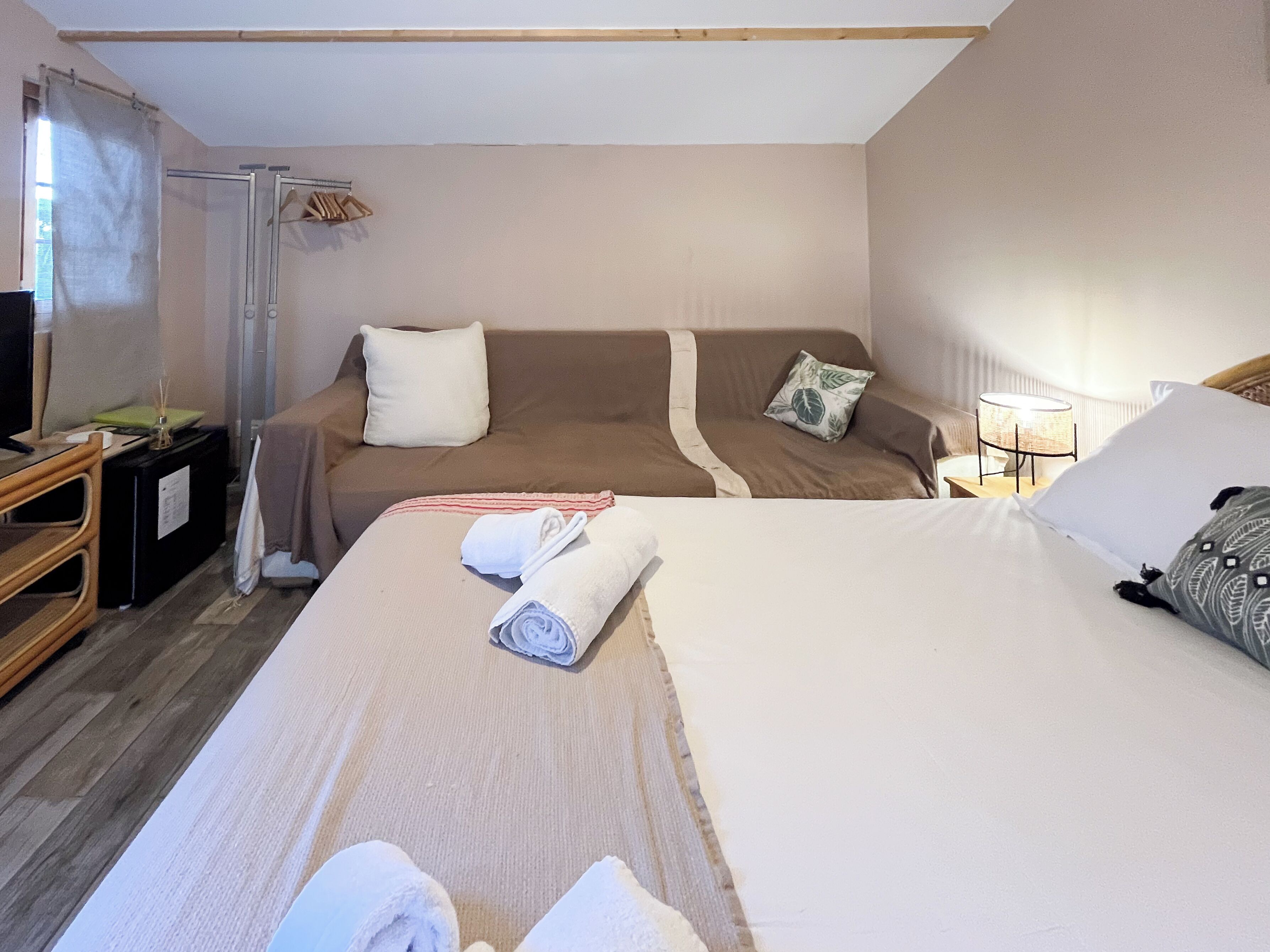 Een hotelkamer met een groot bed, twee banken, een televisie en een klein tafeltje met een lamp.