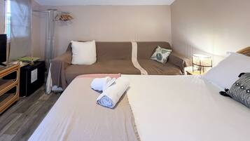 Een hotelkamer met een groot bed, twee banken, een televisie en een klein tafeltje met een lamp.