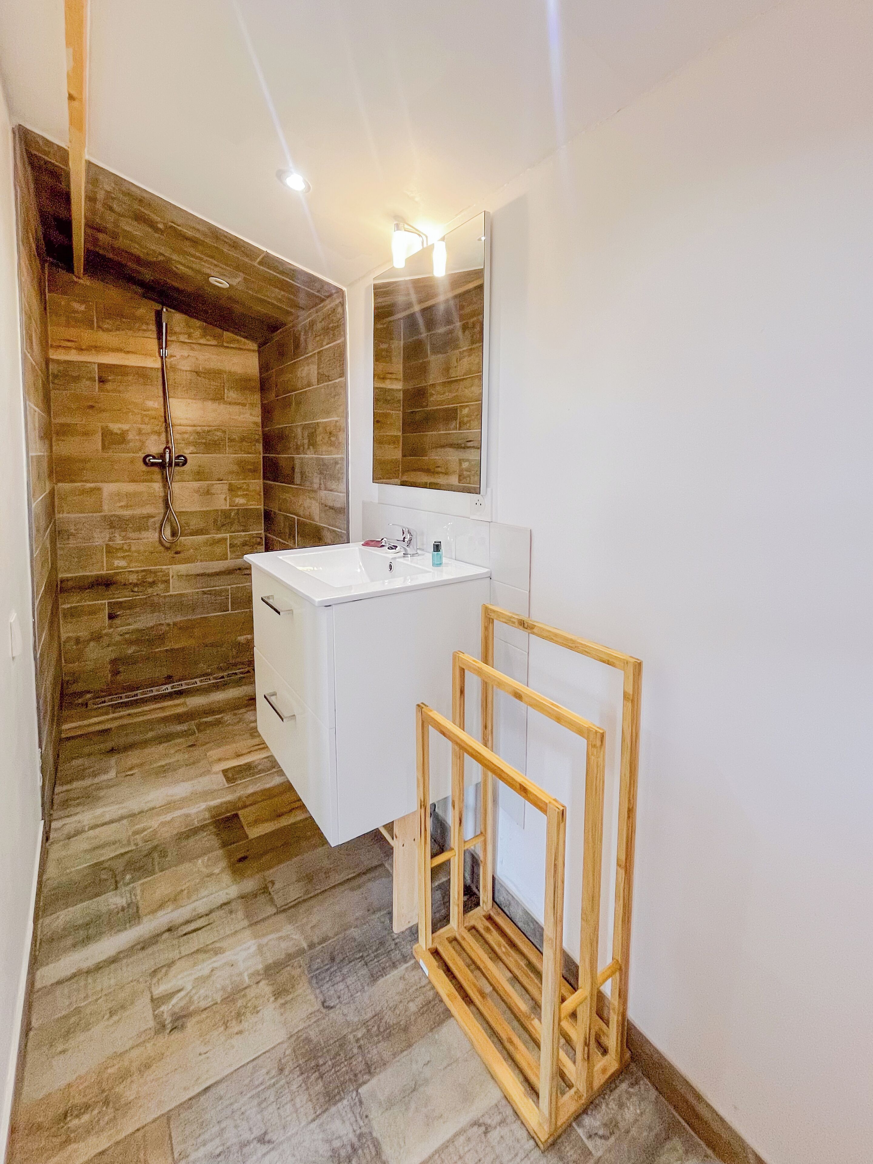 Une salle de bain moderne avec un mur en bois, un lavabo blanc et une douche.