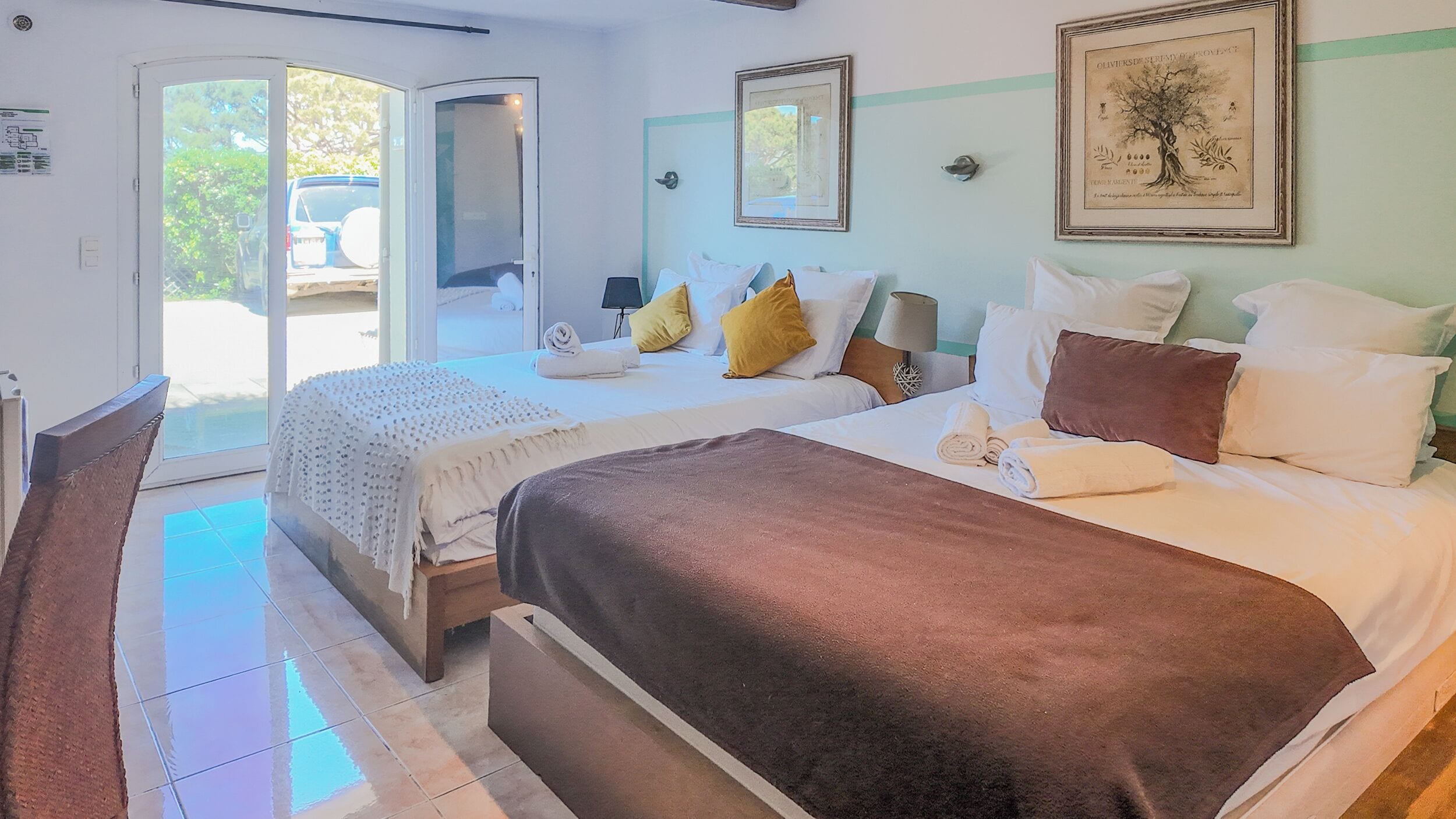Una habitación de hotel con dos camas, un ventanal grande y una puerta que da al exterior.