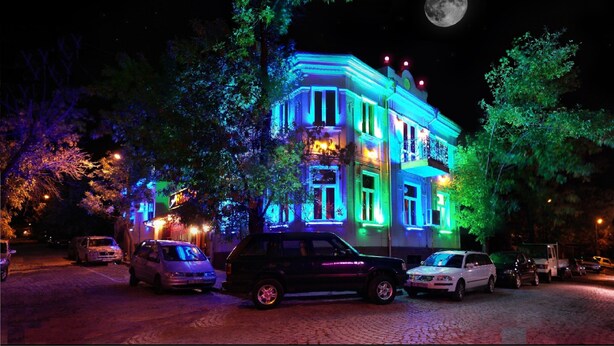 Un edificio con ventanas iluminadas y una luna en el cielo.