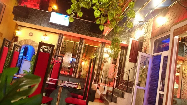 A hotel lobby with a staircase, red seating, and hanging plants.