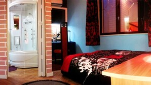Un dormitorio con cama, escritorio, silla, baño con ducha y armario de madera.