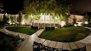 A landscaped garden with a circular lawn, pathways, and a building with illuminated windows. - Dom Aktera (Odesa)