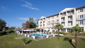 A hotel with a swimming pool, outdoor seating, and a well-maintained garden.