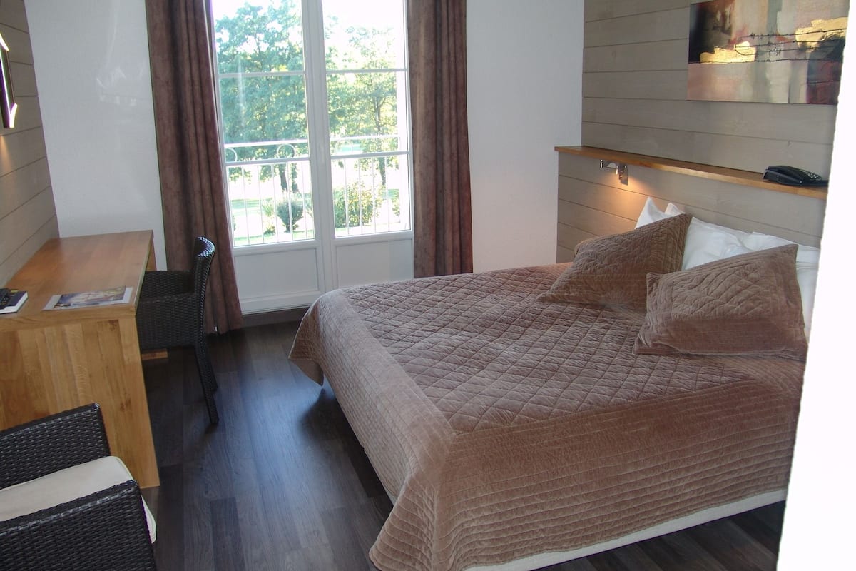 A bedroom with a bed, a desk, and a chair.