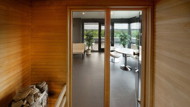 A wooden interior with a view to an outdoor balcony area. - GMP Clubhotel Apartments (Otepaa)