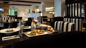 A restaurant with a modern interior, featuring striped chairs and a variety of dishes on the tables. - GMP Clubhotel Apartments (Otepaa)