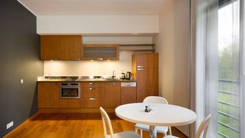 Una cocina moderna con armarios de madera, horno empotrado y un comedor con una mesa redonda y sillas.