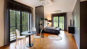 A modern bedroom with a large bed, a TV, and a dining area with chairs and a table. - GMP Clubhotel Apartments (Otepaa)