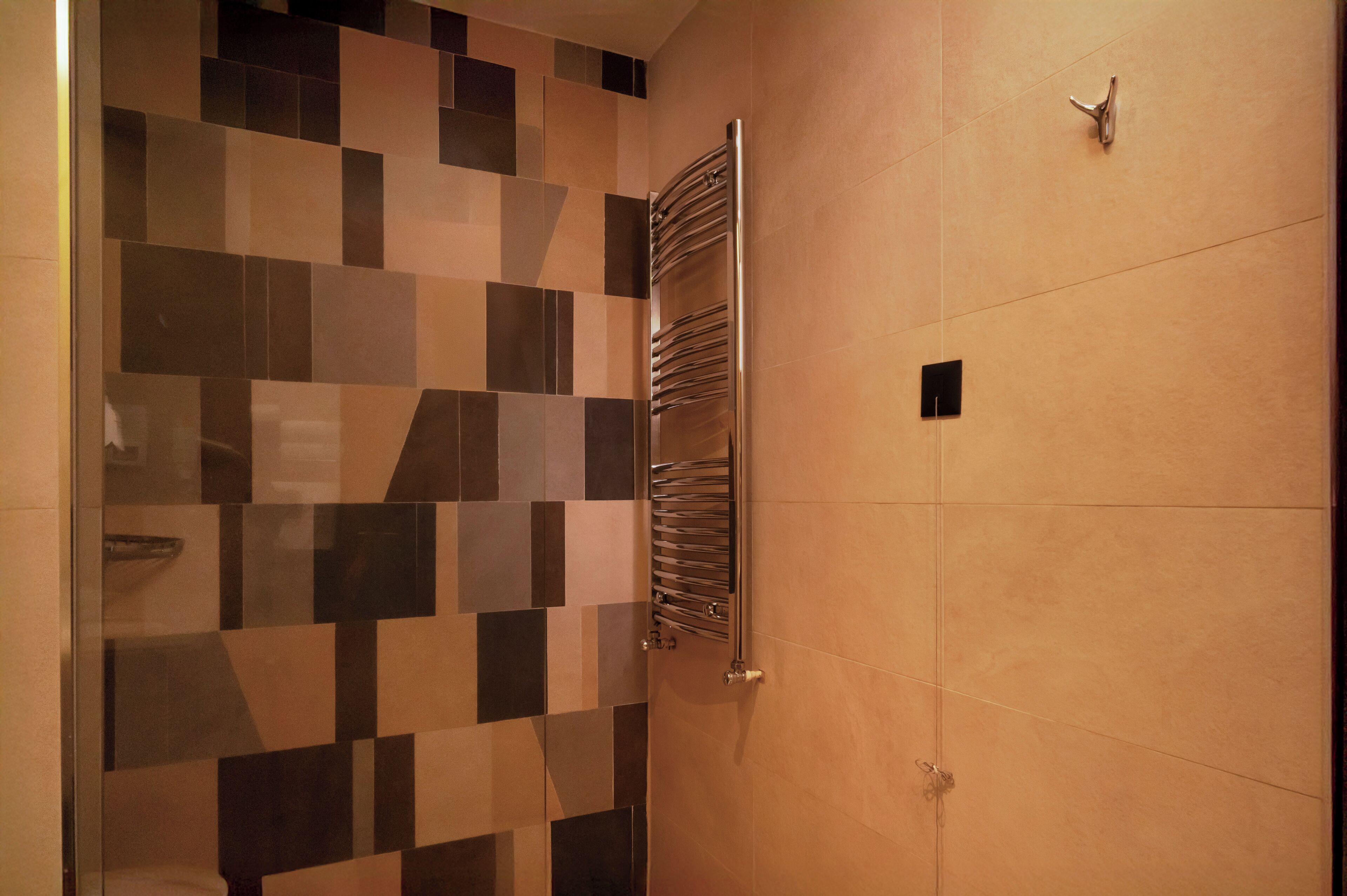 A bathroom with a tiled wall, a towel rack, and a door handle.