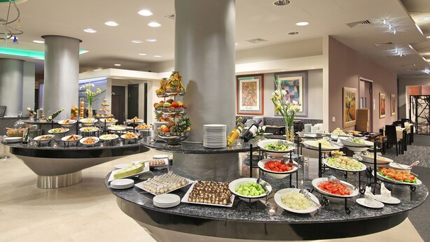 Montaje de bufé con diferentes alimentos y una columna decorativa central.