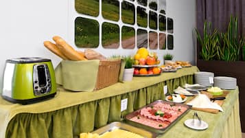 Una mesa de buffet con diversos alimentos, un tostador y una pared con múltiples cuadros enmarcados.