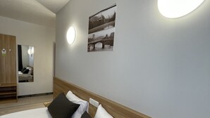 A hotel room with two beds, a wooden headboard, a mirror, and a wall-mounted picture. - Green Vilnius Hotel (Vilnius)