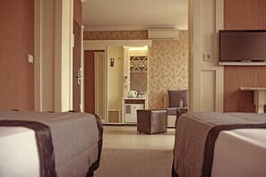 A hotel room with two beds, a kitchenette, a TV, and a bathroom visible through an open door. - Park Hotel Plovdiv (Plovdiv)